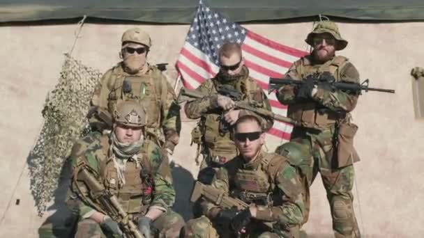 Retrato médio de jovens oficiais de inteligência dos EUA em camuflagem juntos segurando rifles com bandeira dos EUA lisonjeiro no fundo - Filmagem, Vídeo