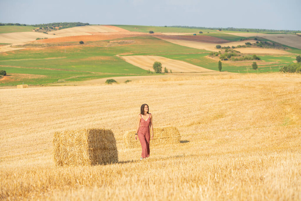 Jolie et souriante jeune fille aux cheveux bouclés. Marcher dans un champ de blé. - Photo, image