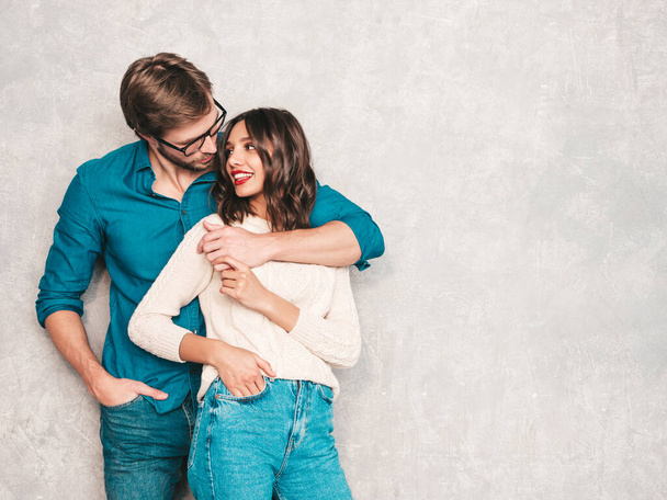 Portrait of smiling beautiful woman with red lips and her handsome boyfriend. Happy cheerful family posing in studio near gray wall.Valentine's Day. Models hugging. Concept of love - 写真・画像