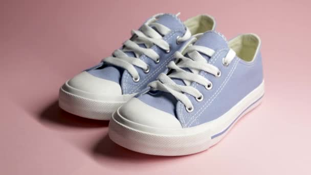 Para nowych niebieskich tenisówek, buty sportowe na różowym tle. - Materiał filmowy, wideo
