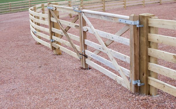 Деревянный забор вокруг сельской местности с новыми деревянными фермерскими воротами. - Фото, изображение