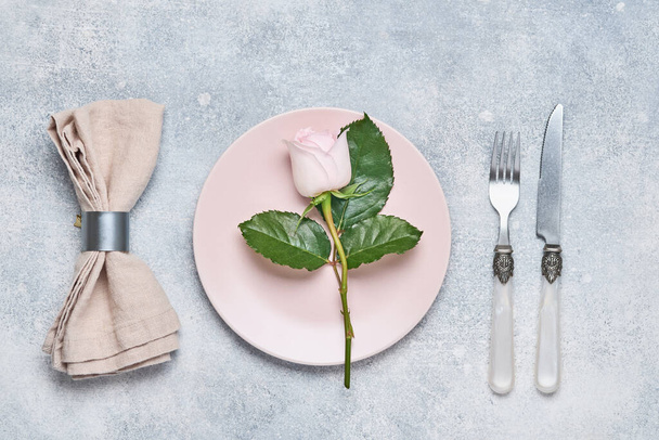 Elegance table setting with pink plate decorated rose flowers on grey background. Elegance holiday dinner. Top view. Space for text. - Foto, immagini