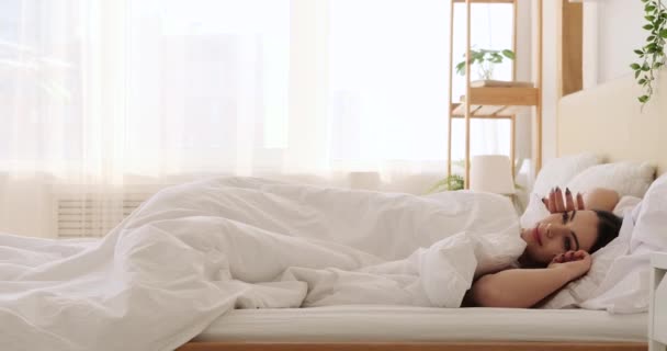 Όμορφη γυναίκα ξυπνά και τεντώνεται στο κρεβάτι - Πλάνα, βίντεο