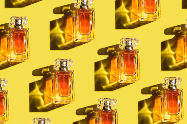 A pattern of woman perfume on the illuminating yellow background, top view, flat lay. Trend color of the year 2021. Mockup of fragrance perfume bottles - Photo, Image