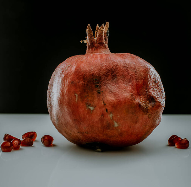 One red pomegranate on a light table  - Foto, Imagem