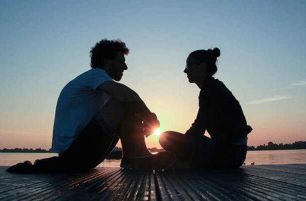 couple looking at each other during a sunset in front of the sea - Fotó, kép