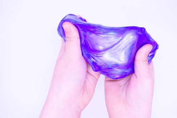 Close up of game with two-color blue and pink slime in someones hands on a white background. The mucus is crushed, stretched, torn and squeezed by hands. - Photo, Image