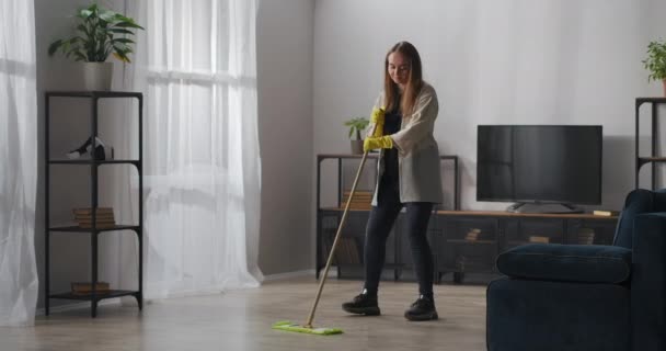 fröhliches Teenie-Mädchen tanzt beim Putzen mit Wischmopp, hilft bei Haus und Waschgang, Freude und Spaß bei der Hausarbeit - Filmmaterial, Video