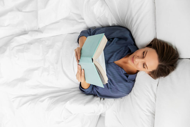 young woman reading book in bed at home - Foto, Bild