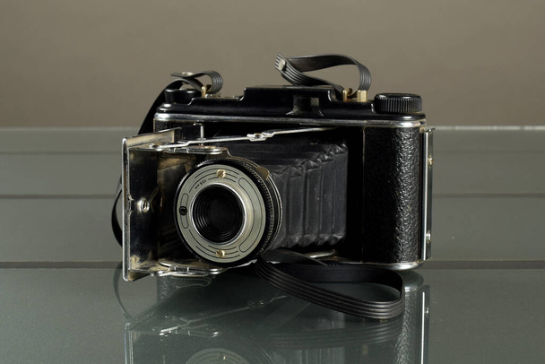 Старая ретро-фотокамера на темном черном столе. Старая фотокамера в студии - Фото, изображение