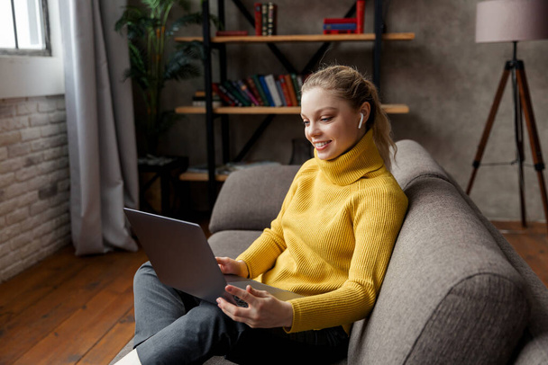 Genç bir kadın evdeki dizüstü bilgisayarında video görüşmesi yapıyor. - Fotoğraf, Görsel