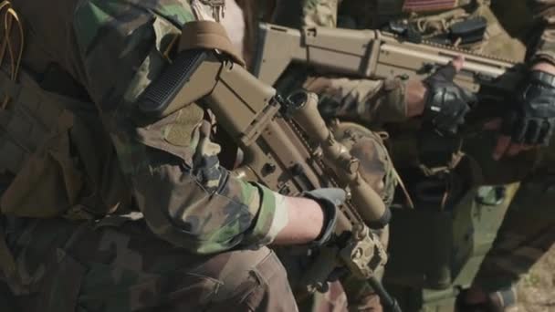 Inclinando-up close-up de corpo de inteligência em roupas de camuflagem segurando espingardas enquanto avalia a situação em operação militar - Filmagem, Vídeo