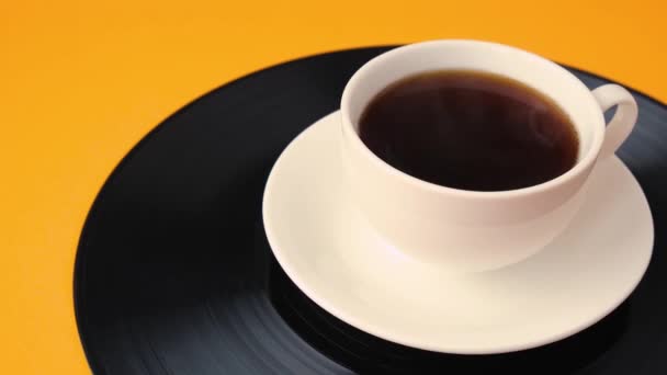 Cup of black coffee is on vinyl record. Steaming Cup of coffee. - Footage, Video