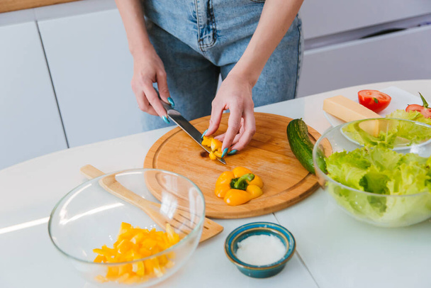 Las manos femeninas cortan verduras frescas en una ensalada dietética. Un plato de pimientos dulces y tomates con hierbas. Alimentación saludable - Foto, Imagen