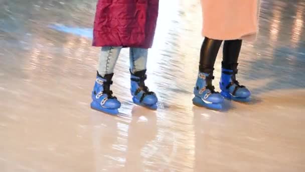 Az emberek korcsolyapályán utaznak. Jégkorcsolyás lábak közelről. Fényfoltok a jégen. 4k felbontású videó. - Felvétel, videó