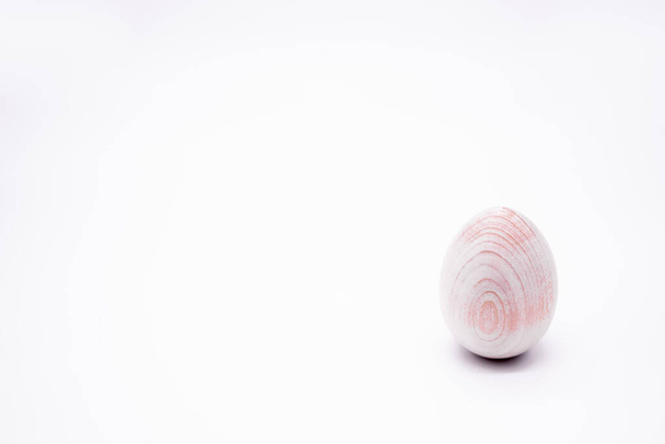 Een onbeschilderd handgemaakt houten ei op een witte achtergrond. Kopieerruimte. - Foto, afbeelding