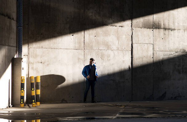 man in casual clothes, on an urban wall sunlight entering and shadows, - Фото, зображення