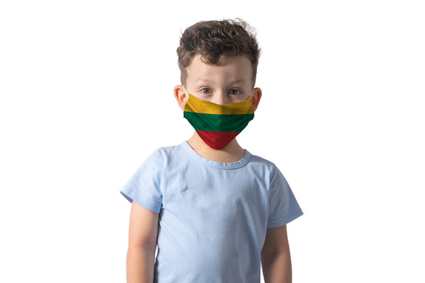 Atemschutzmaske mit litauischer Flagge. Weißer Junge setzt medizinische Gesichtsmaske isoliert auf weißem Hintergrund auf. - Foto, Bild