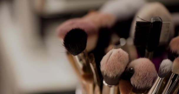 Close-up van verschillende make-up borstels in doos op tafel - Video