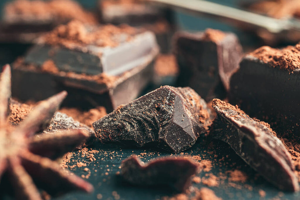 Chocolate chunk, chopped chocolate cubes on dark background, close-up view. - Photo, Image