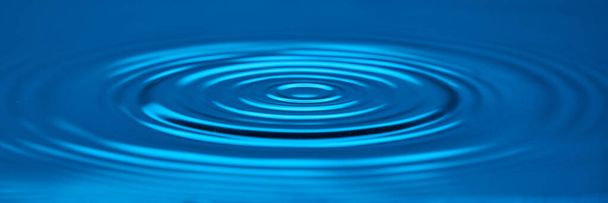 Horizontal shot of blue background smooth circles on the water. - Foto, afbeelding