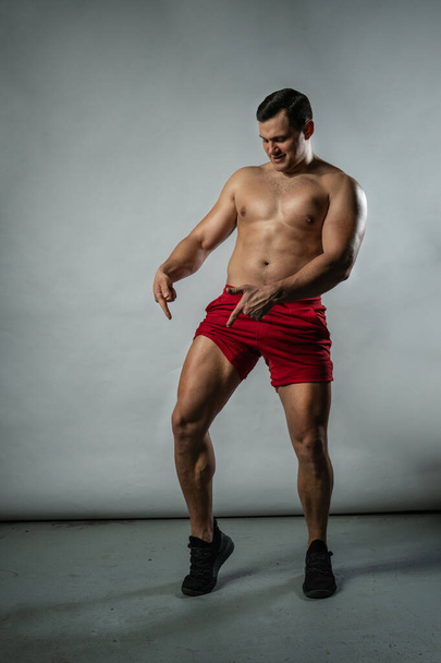 Fitness-Mann zeigt Muskeln auf weißem Hintergrund kaukasische Mode, attraktiver lässiger Bodybuilder. Ernste modische, Hantel einsamen Hintergrund schwarzer Bodybuilder - Foto, Bild