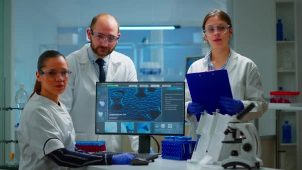 Equipo de científicos sentado en el laboratorio mirando a la cámara - Metraje, vídeo