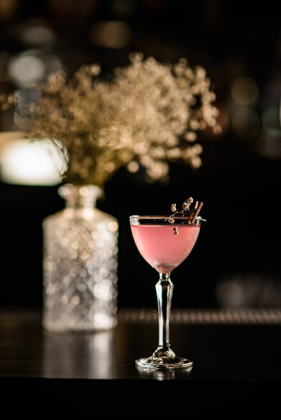 gorgeous glass with cocktail decorated with blooming twig stands on the bar. - Foto, Imagen