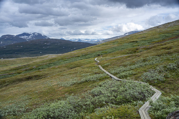 Panorama Mountain landscape and Wide Scenery in Padjelanta National Park with Wet Hiking Trail leading away from Camera during dramatic weather in the Summer in Northern Sweden, Lapland. - Photo, Image