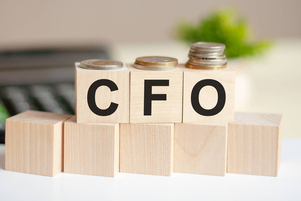 Концептуальні слова CFO на дерев'яних блоках на красивому фоні з доларових купюр. Слово CFO на дерев'яних кубиках з монетами та калькулятором на фоні. Бізнес-концепція. фінансовий директор
 - Фото, зображення