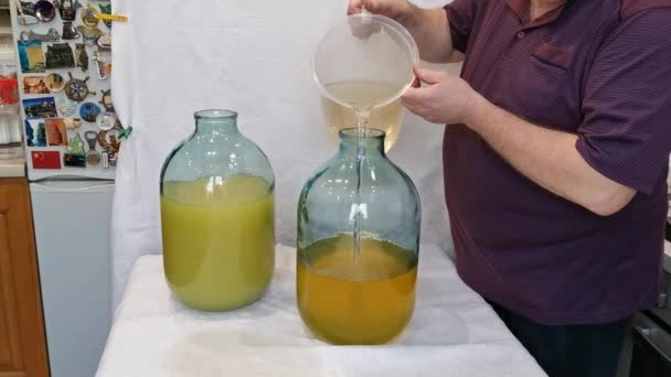 A limoncello citromos likőr készítésének folyamata otthon. Egy férfi citromhéjjal keveri az alkoholt cukorsziruppal egy 10 literes üvegben.. - Felvétel, videó