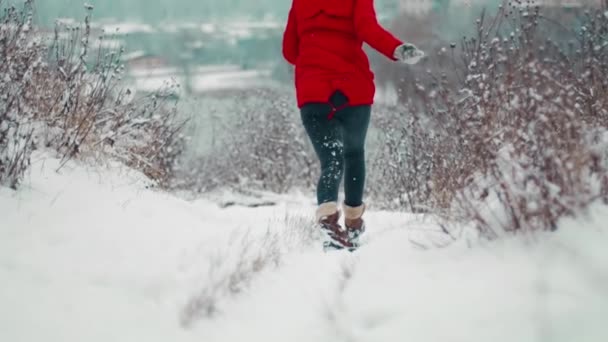 En hiver, une jeune fille glisse ses chaussures sur la neige dans une chute de neige et ne peut résister et tombe au sol frappant durement la tête et les épaules, de douleur et de blessures qu'elle tord sur le côté. - Séquence, vidéo