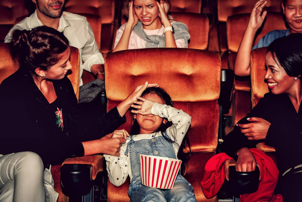 La niña se sentó y lloró en un cine, con un grupo de personas mirando juntos tratando de consolarlo y algunos de ellos se ofendieron. - Foto, imagen