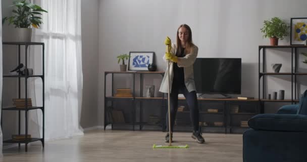 governante femminile sta ballando con lo straccio durante la pulizia della casa, lavaggio del pavimento, gioia e divertimento durante i lavori domestici - Filmati, video