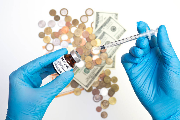 Coronavirus vaccine cost. vaccine ampoule with syringe in hand and money. Fight against Covid-19. Pevention, immunization and treatment concept, flat lay - 写真・画像