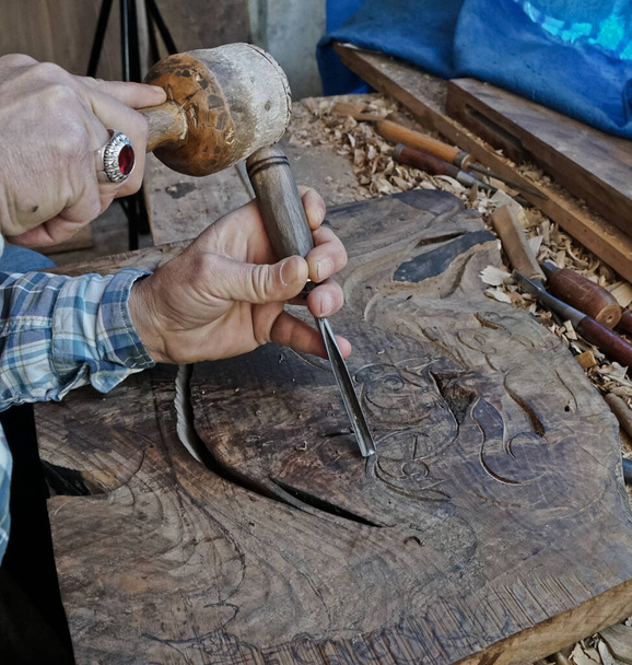 Tallado en madera. Talla con cincel y martillo. Un hábil artesano trabajando en un panel de decoración de talla de madera - Foto, Imagen
