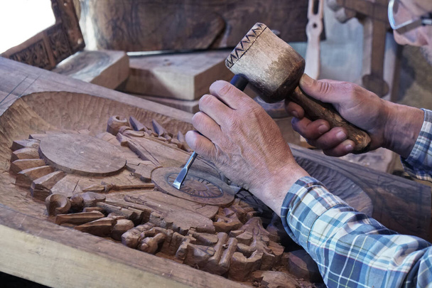 Rzeźbienie w drewnie. Rzeźba z dłutem i młotkiem. Zręczny rzemieślnik pracujący na desce dekoracji rzeźby w drewnie - Zdjęcie, obraz