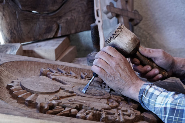 Vyřezávání dřeva. Carver s dlátem a kladivem. Dovedný řemeslník pracující na desku dřevěné řezbářské výzdoby - Fotografie, Obrázek