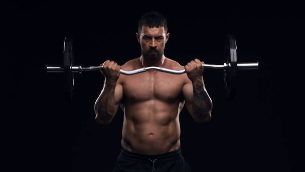 Fit and sporty bodybuilder over black background. Sportsman in studio. Sport and fitness concepts. - Фото, зображення