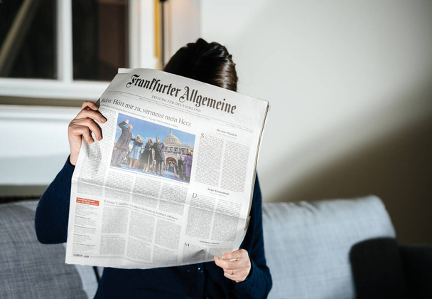 Woman reading Frankfurter Allgemeine German newspaper featuring breaking news and headlines with Joe Biden - Foto, Imagen