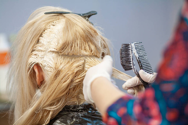 Fodrászat, fodrászat, fodrászat, fodrászat, egy fiatal európai nő világos tónussal festi a haját. - Fotó, kép
