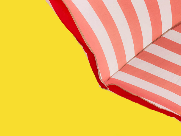 Part of a striped beach umbrella against a color of the year 2021 Illuminating, bottom view. Minimal summer concept. - Photo, Image