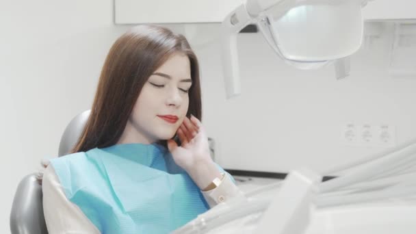 Mujer joven que sufre de dolor de muelas sentado en la silla dental - Imágenes, Vídeo