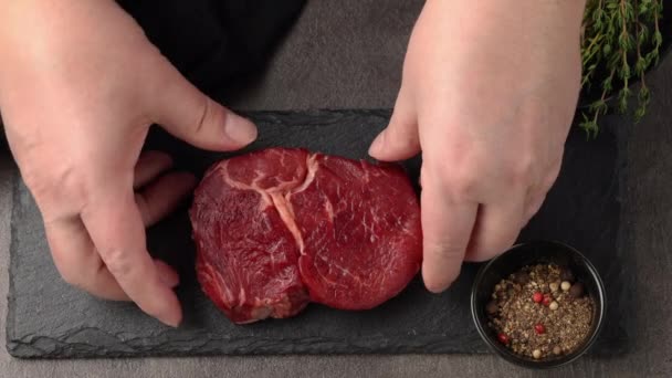 cook add salt pepper and thyme to fresh raw beef steak meat for grilling, top view close up - Filmagem, Vídeo