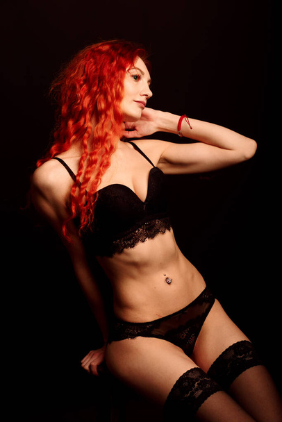 Сексуальная женщина в нижнем белье на черном фоне, рыжие волосы - Фото, изображение