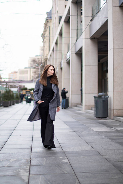 Stylish woman walks through the city in a coat. Free space for text - Photo, Image