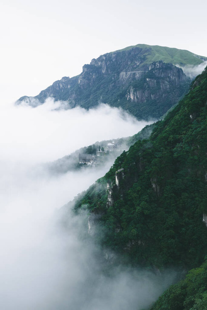 Горные хребты и деревня покрыты туманом на горе Угун (Угуншань) в Цзянси, Китай - Фото, изображение