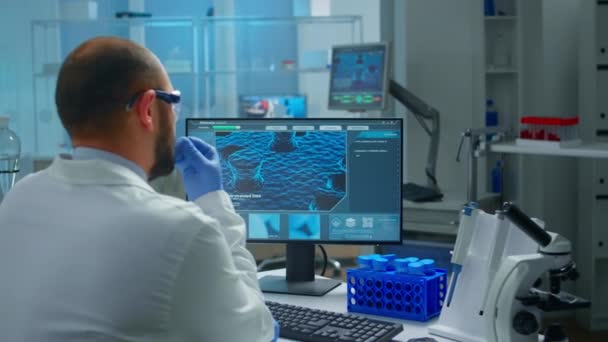 Zaniepokojony lekarz chemik pracujący nad pc badającym ewolucję szczepionki - Materiał filmowy, wideo