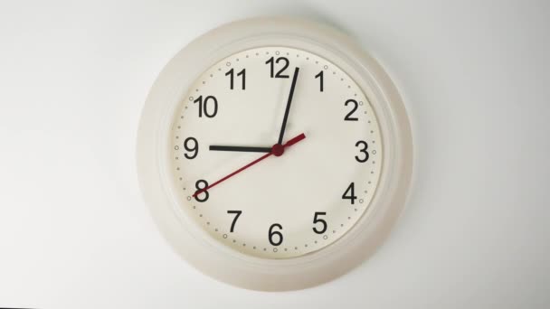 Biały zegar ścienny wskazuje godzinę. Obroty krótkich i długich rąk zegara. Na białym tle. - Materiał filmowy, wideo