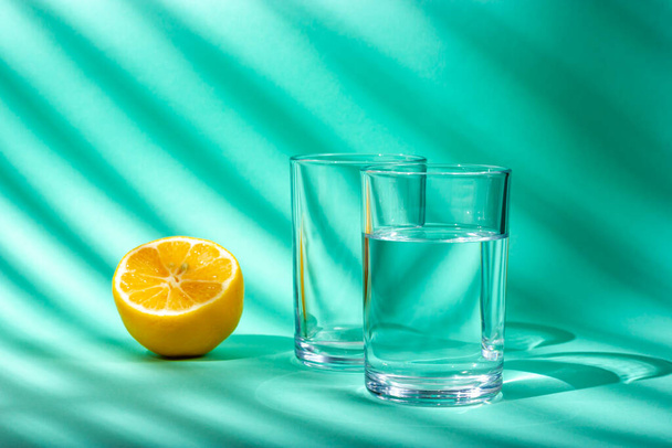 A glass of water and half a lemon. Sunlight. Light from the window. - 写真・画像